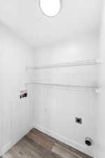 Dedicated utility space featuring wood-finish flooring, white baseboards, and bright white walls
