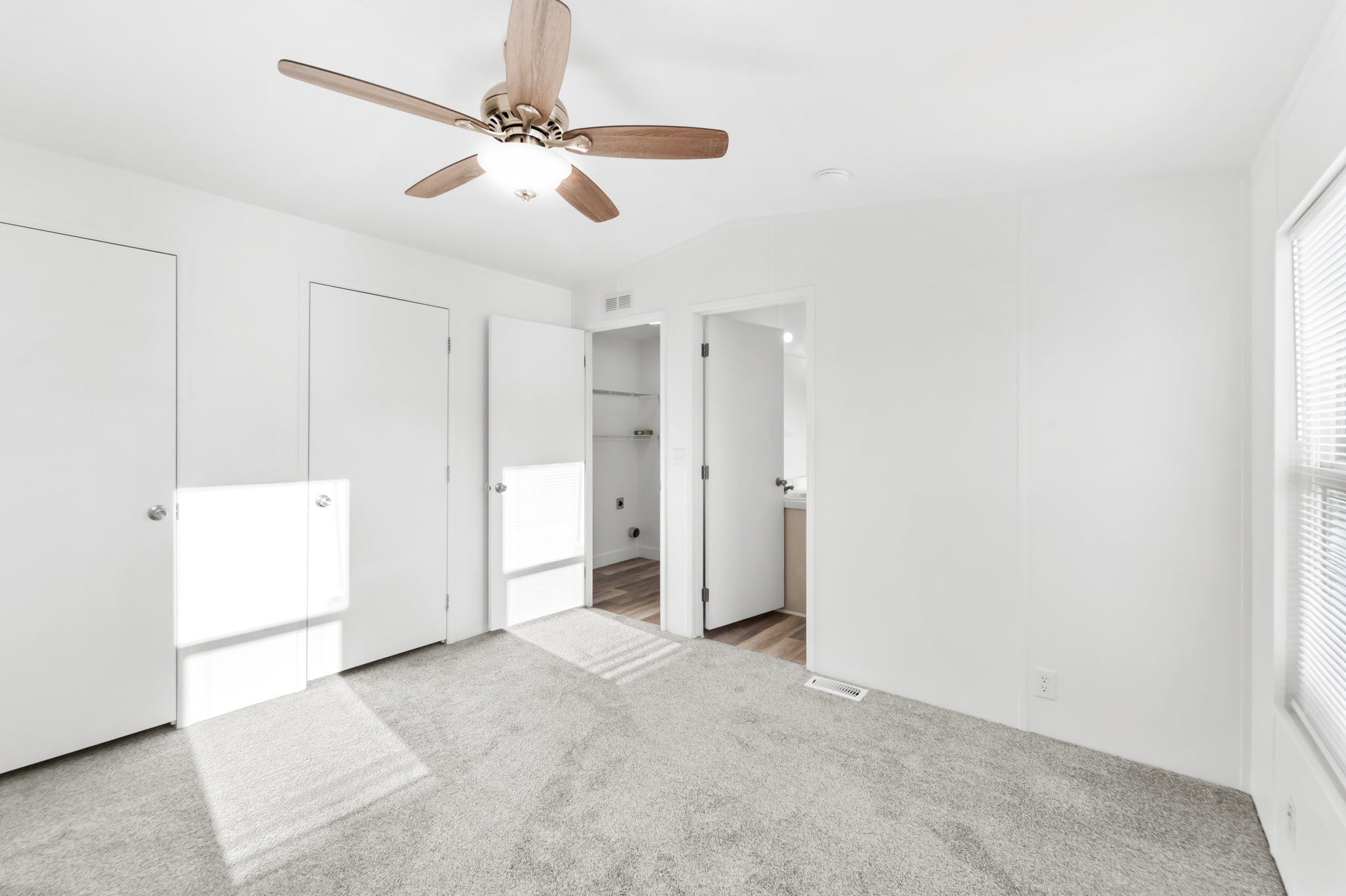 Carpeted bedroom with a wood-finish ceiling fan and light fixture