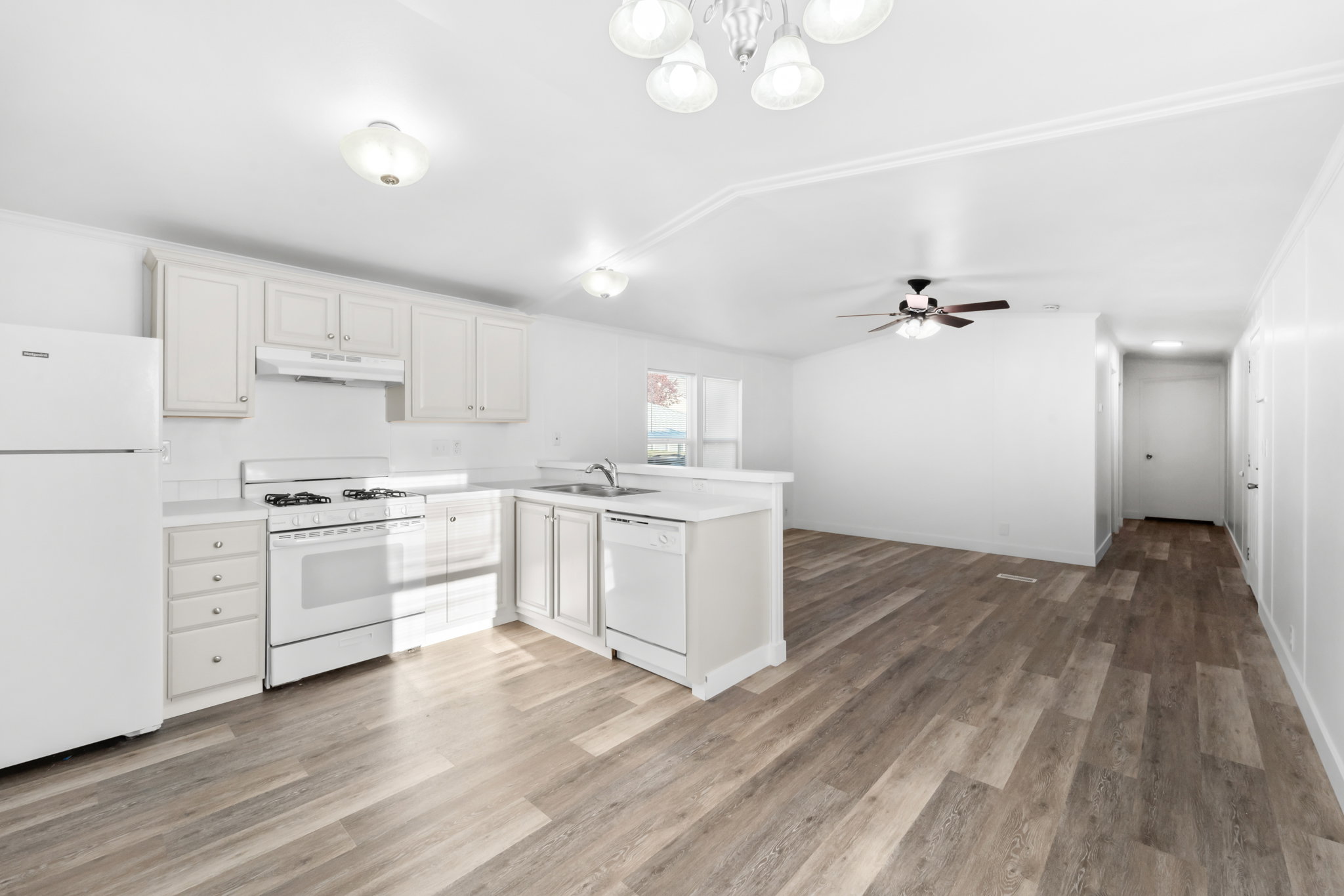 Kitchen featuring white cabinetry, white appliances, laminate countertops, and wood-finish flooring