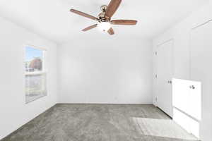 Neutral white walls complemented by a vaulted ceiling with a ceiling fan