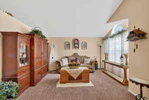 Spacious living area featuring vaulted ceilings, a large arched window, and neutral wall tones