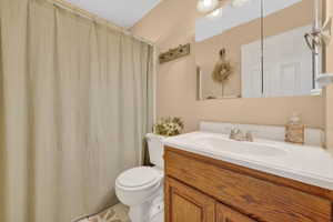 Bathroom featuring a wood-finish vanity with a white countertop and integrated sink, a mirrored medicine cabinet, and overhead vanity lighting