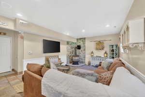 Living area featuring a stone accent wall with a wood-burning stove, recessed lighting, and wall-mounted shelving