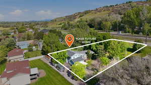 Aerial perspective highlighting a light blue residence with a dark roofline, mature landscaping, and an expansive lot