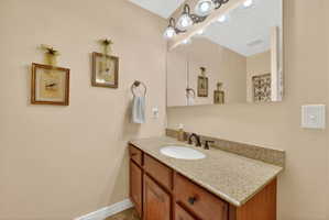 Bathroom vanity with a granite-finish countertop, undermount sink, and dark bronze-finish fixtures