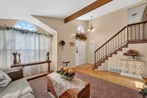 Entryway featuring a grand staircase with wrought iron balusters and wood handrails, hardwood flooring, and a double-hung arched window