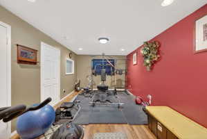 Dedicated fitness area featuring durable wood-finish flooring, recessed lighting, and a window