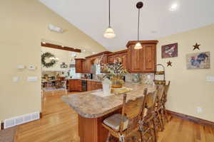 Spacious kitchen featuring a large island with seating, pendant lighting, wood cabinetry, and a tile backsplash