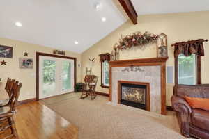 Vaulted ceiling with exposed wood beams, recessed lighting, and a stone-surround fireplace with a wood mantle