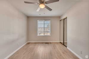 Unfurnished bedroom featuring light wood-style floors, a closet, and ceiling fan