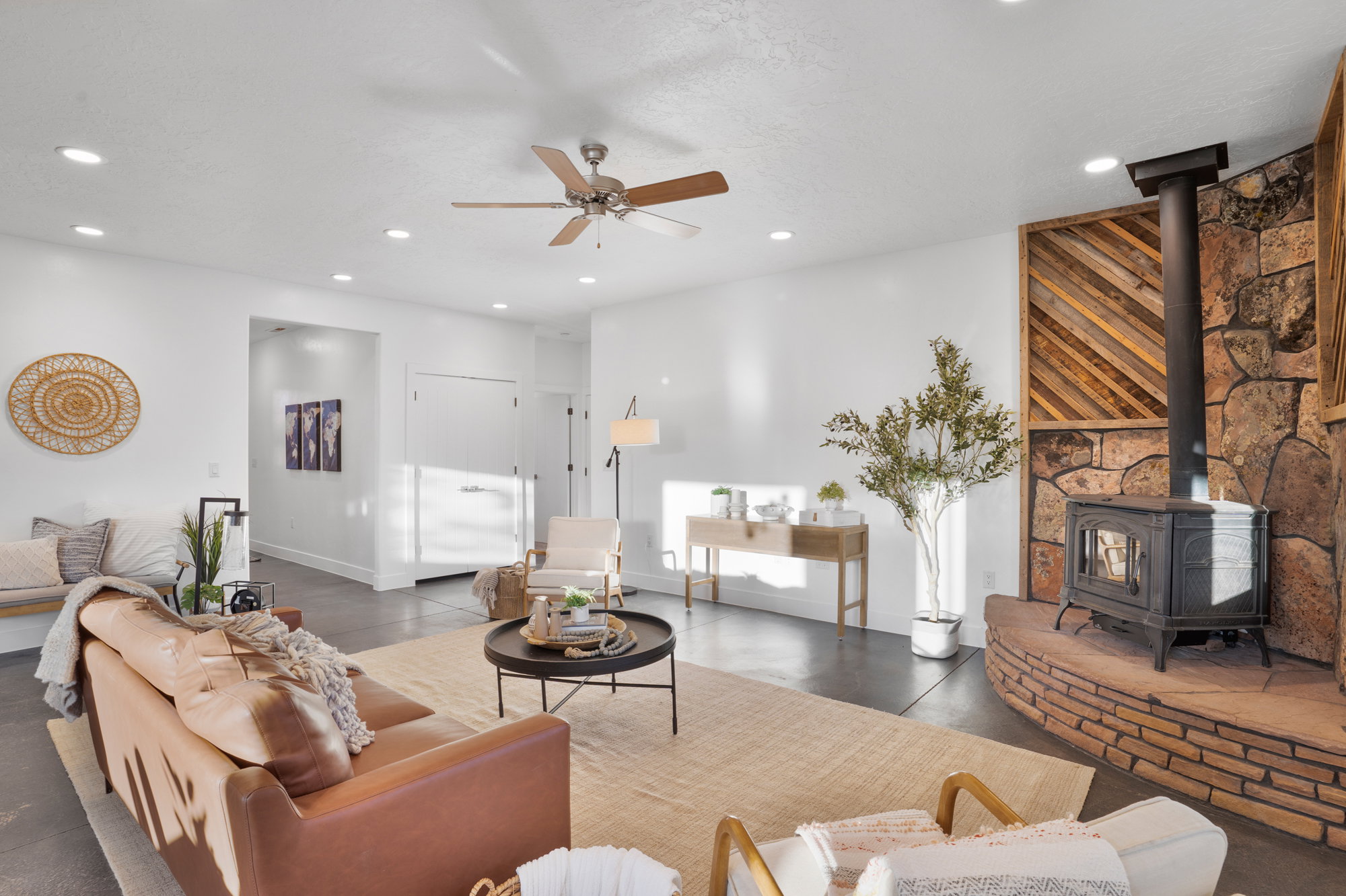 Living area featuring a stone fireplace with a wood-burning stove, a diagonal wood accent wall, recessed lighting, and a ceiling fan