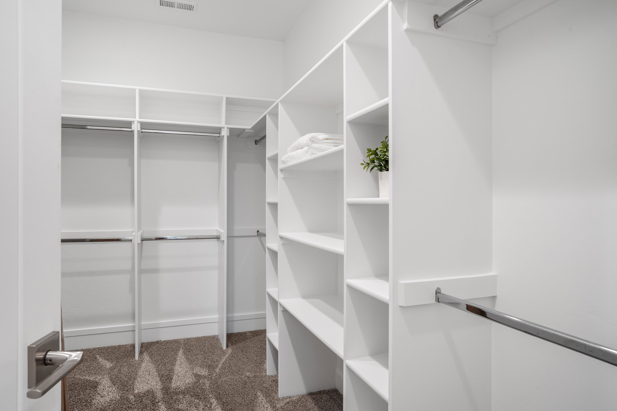 Custom closet system with white shelving, multiple hanging rods, and integrated storage