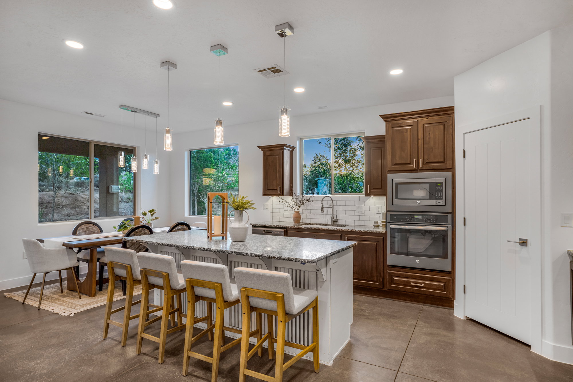 Kitchen featuring a central island with a stone countertop, built-in stainless steel appliances, dark wood-finish cabinetry, a subway tile backsplash, and recessed lighting