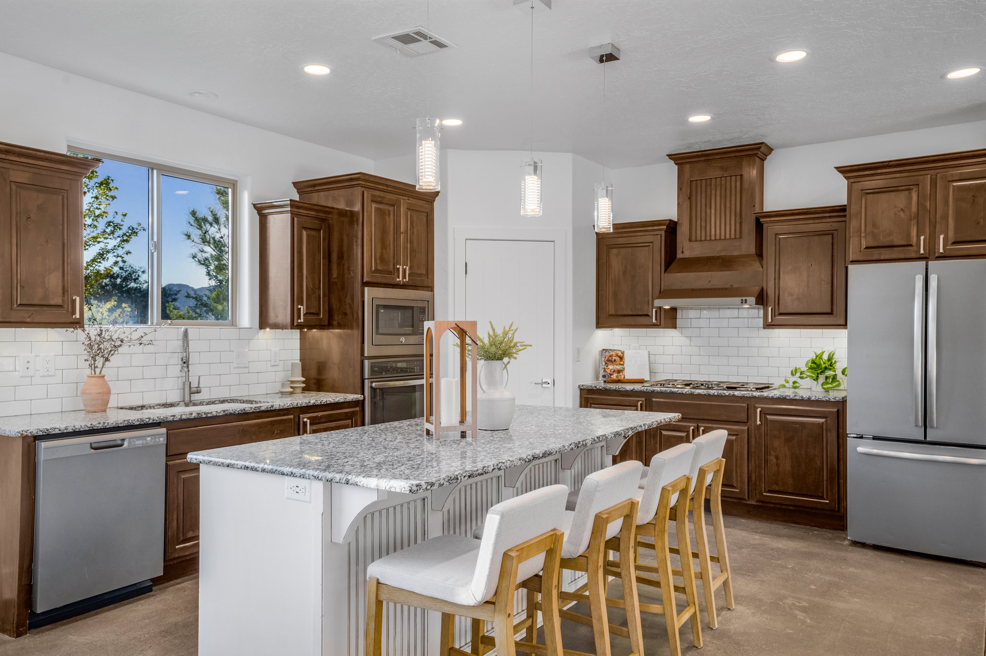 Kitchen featuring a central island with granite countertop, wood-finish cabinetry, stainless steel appliances, subway tile backsplash, and recessed lighting