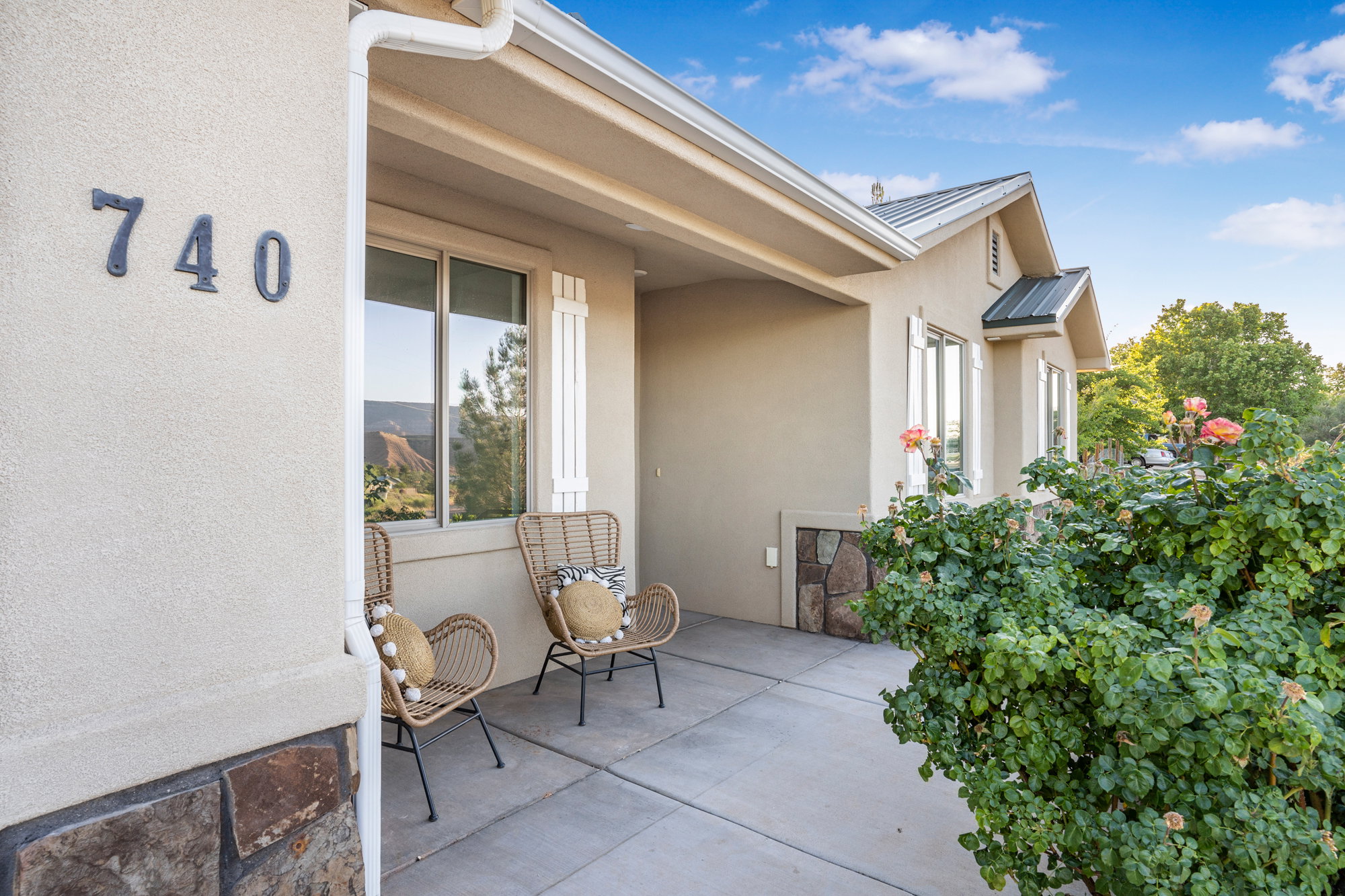 Stucco exterior featuring decorative shutters and a stone veneer accent