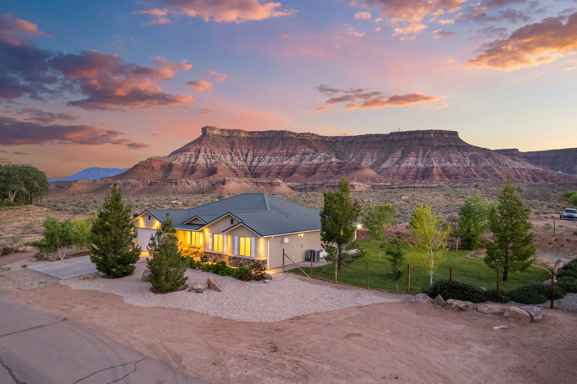 Ranch-style residence featuring a green roof, stone accents, and an attached two-car garage