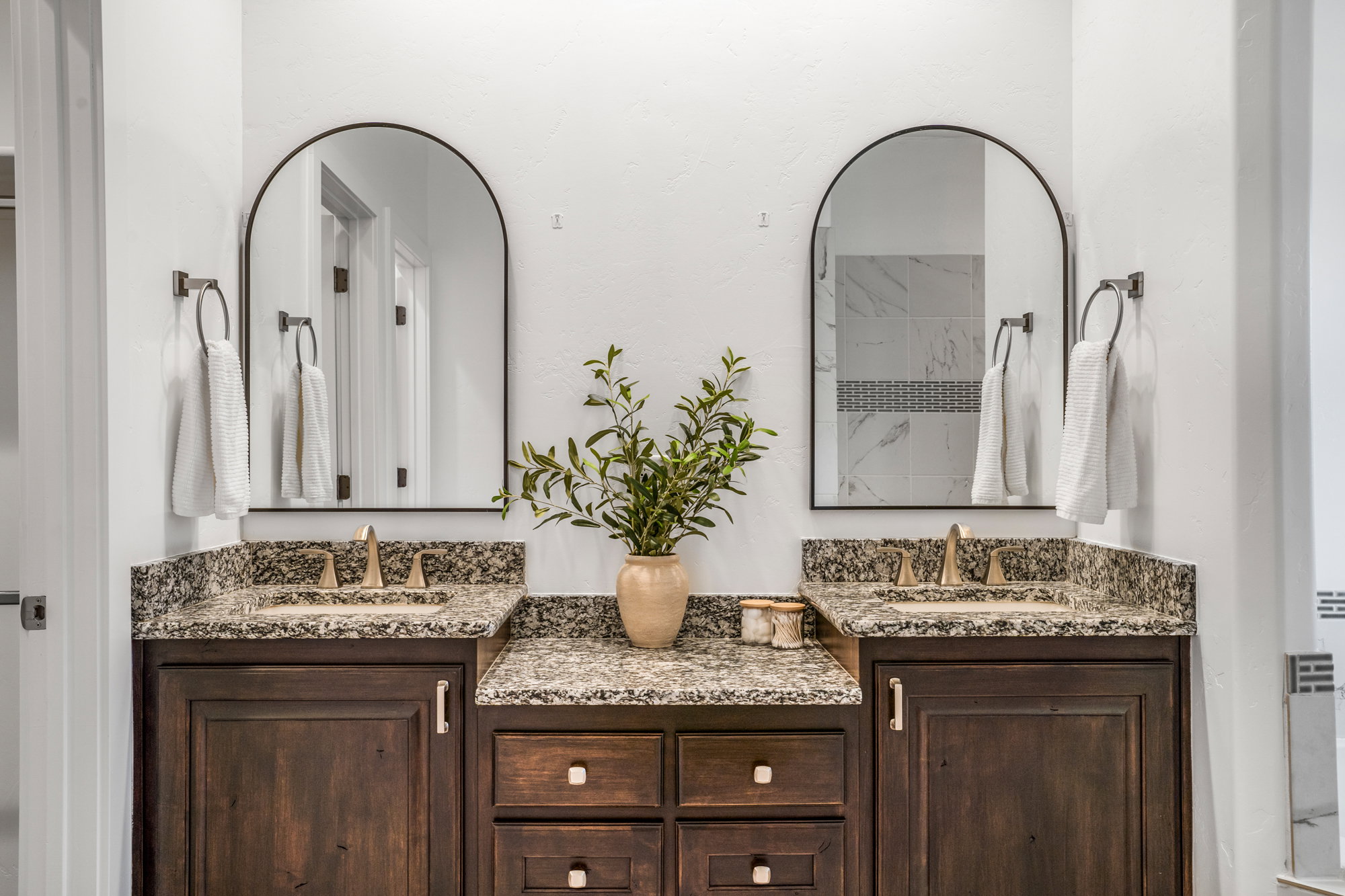 Dual vanity featuring dark wood cabinetry and speckled countertops