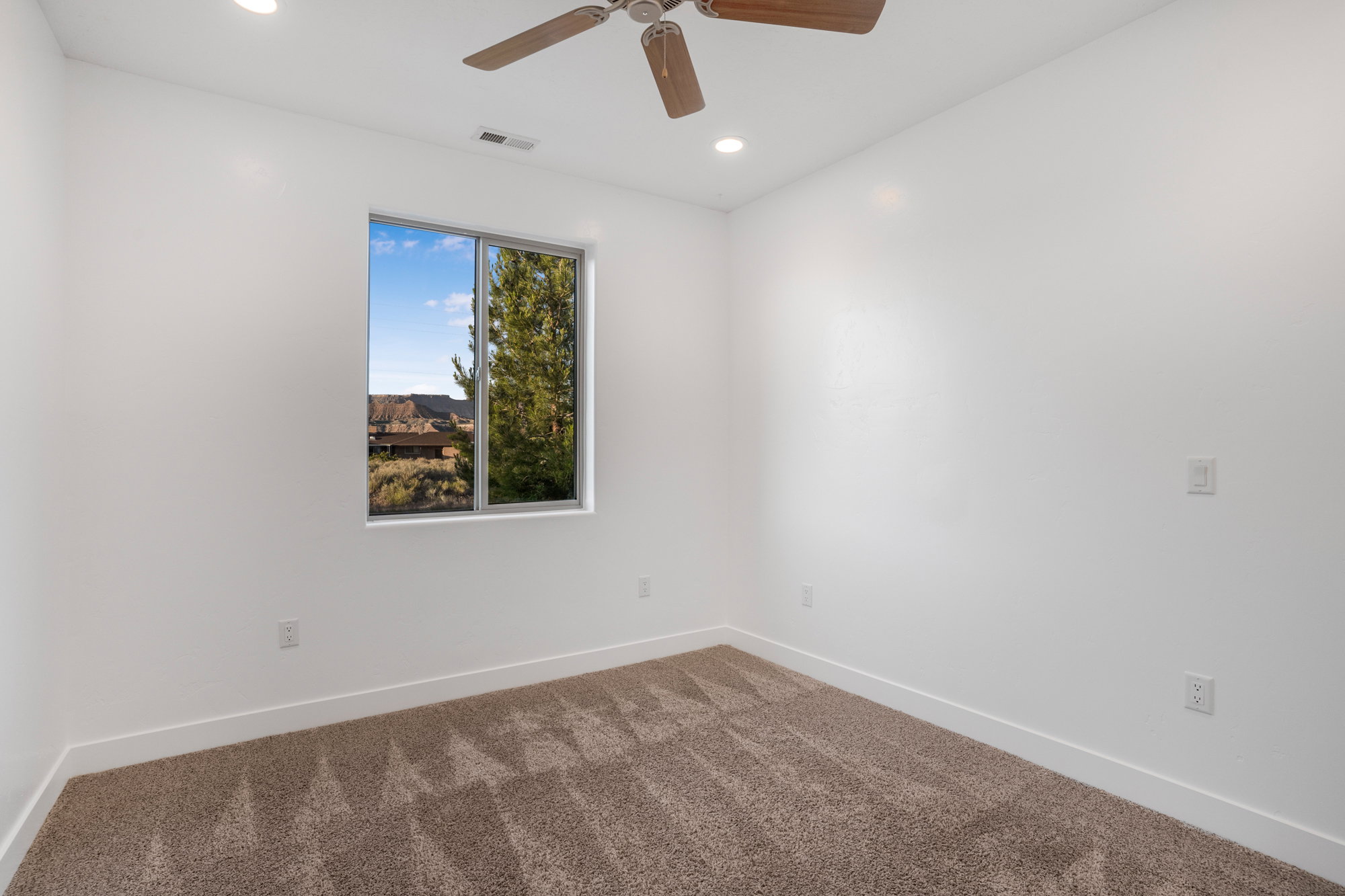Bright room featuring plush patterned carpet, recessed lighting, and a ceiling fan