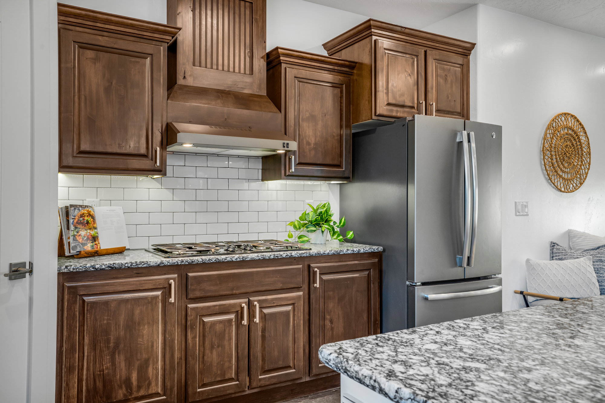 Kitchen featuring dark wood cabinetry, a white subway tile backsplash, granite countertops, and stainless steel appliances including a refrigerator and gas range