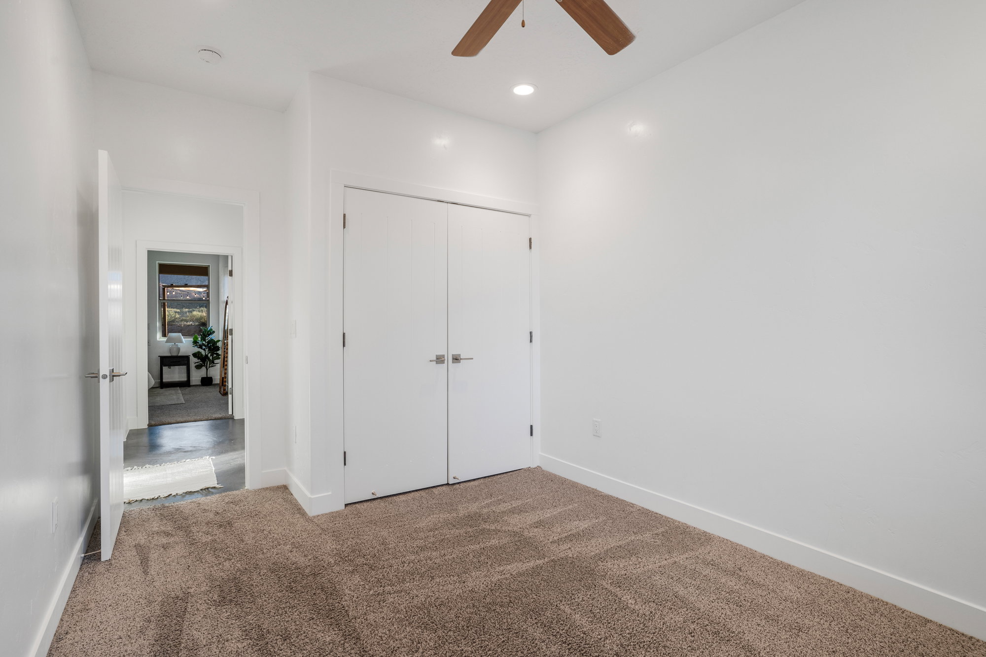Carpeted interior room with white walls, white baseboards, and a bi-fold closet
