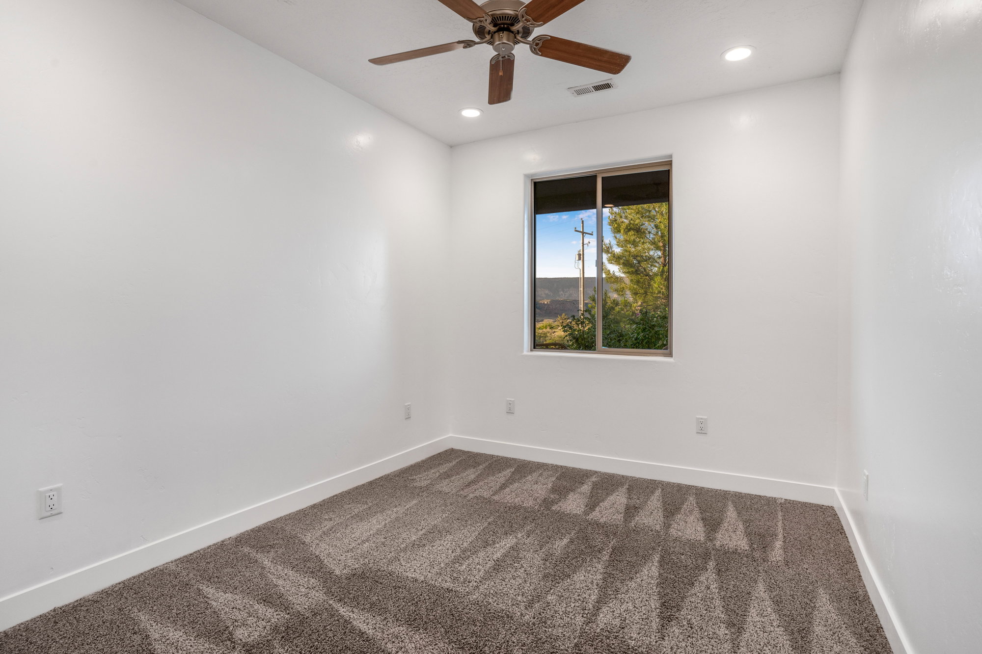 Bedroom featuring a window with a natural landscape backdrop, patterned carpet flooring, recessed lighting, a ceiling fan, and white baseboards