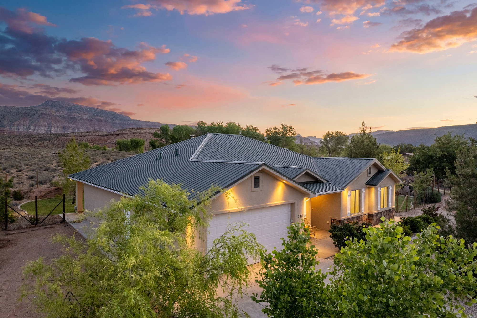Single-story home featuring a green metal roof, light-toned stucco exterior, and a two-car garage