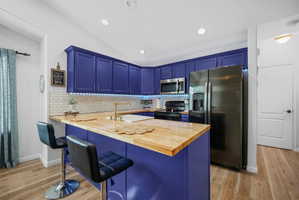 Updated kitchen with butcher block countertops, subway tile backsplash, farmhouse sink, modern lighting