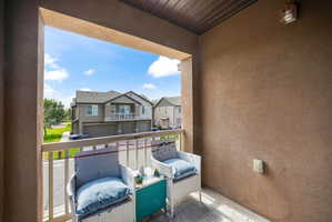 Outdoor balcony featuring a stucco exterior, a wood-paneled ceiling, and a mounted exterior light fixture