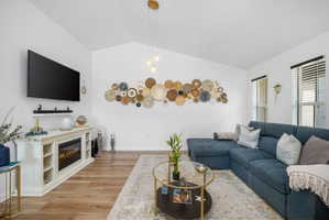 Spacious living area featuring vaulted ceilings, wood-finish flooring, and multiple windows with blinds
