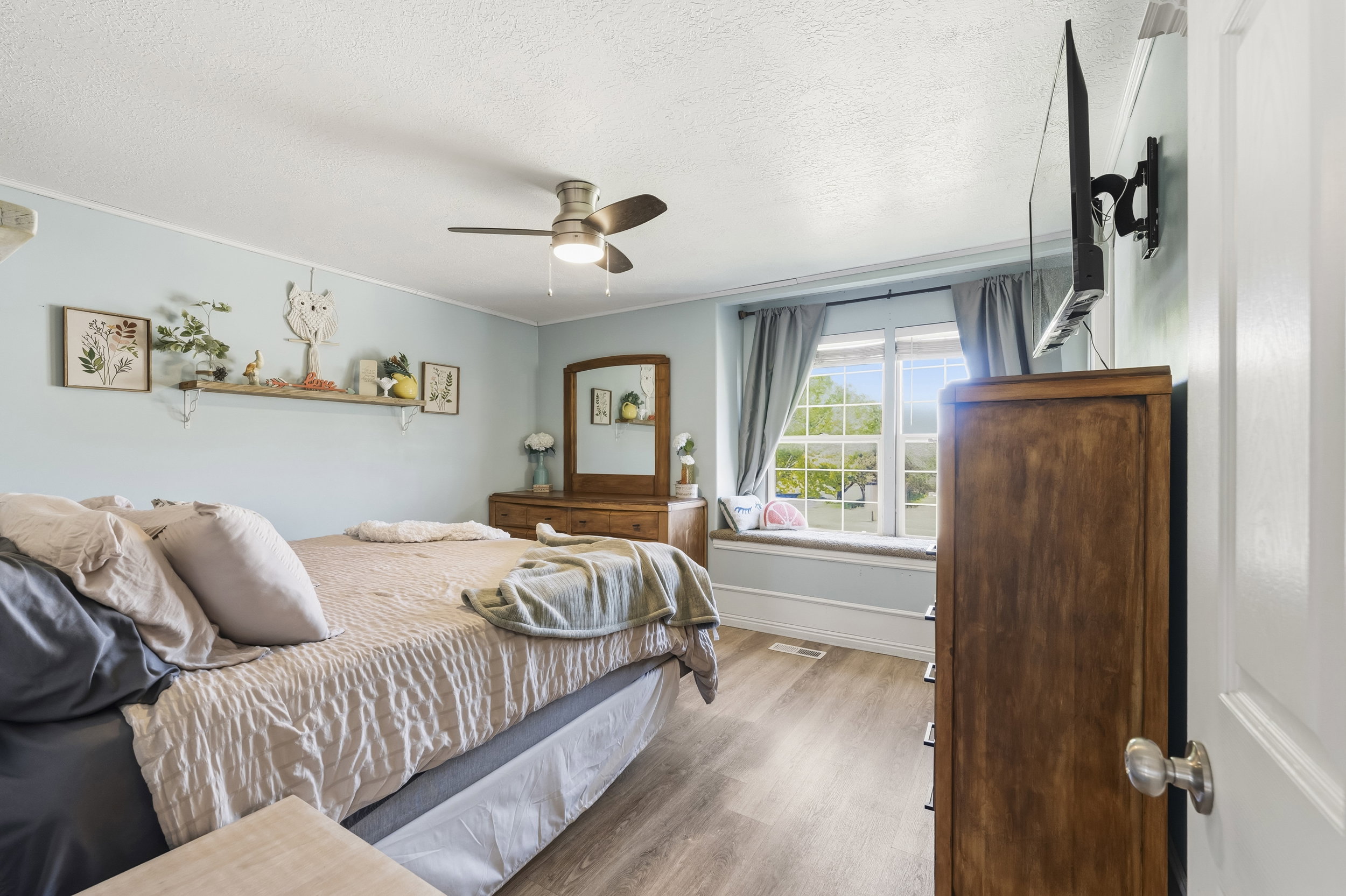 Bedroom featuring wood-finish flooring, a window seat with a cushioned top, and a ceiling fan