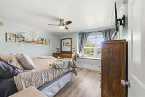 Bedroom featuring wood-finish flooring, a window seat with a cushioned top, and a ceiling fan