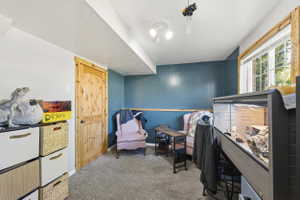 Carpeted room featuring a natural wood door, painted accent wall, white trim, a double-paned window, and a built-in recessed ceiling light fixture