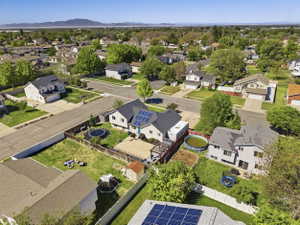 Two-story residence featuring solar panels, a fenced backyard, and a paved patio area