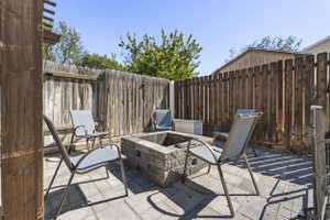 Paved patio area featuring a stone block fire pit, surrounded by a wood privacy fence