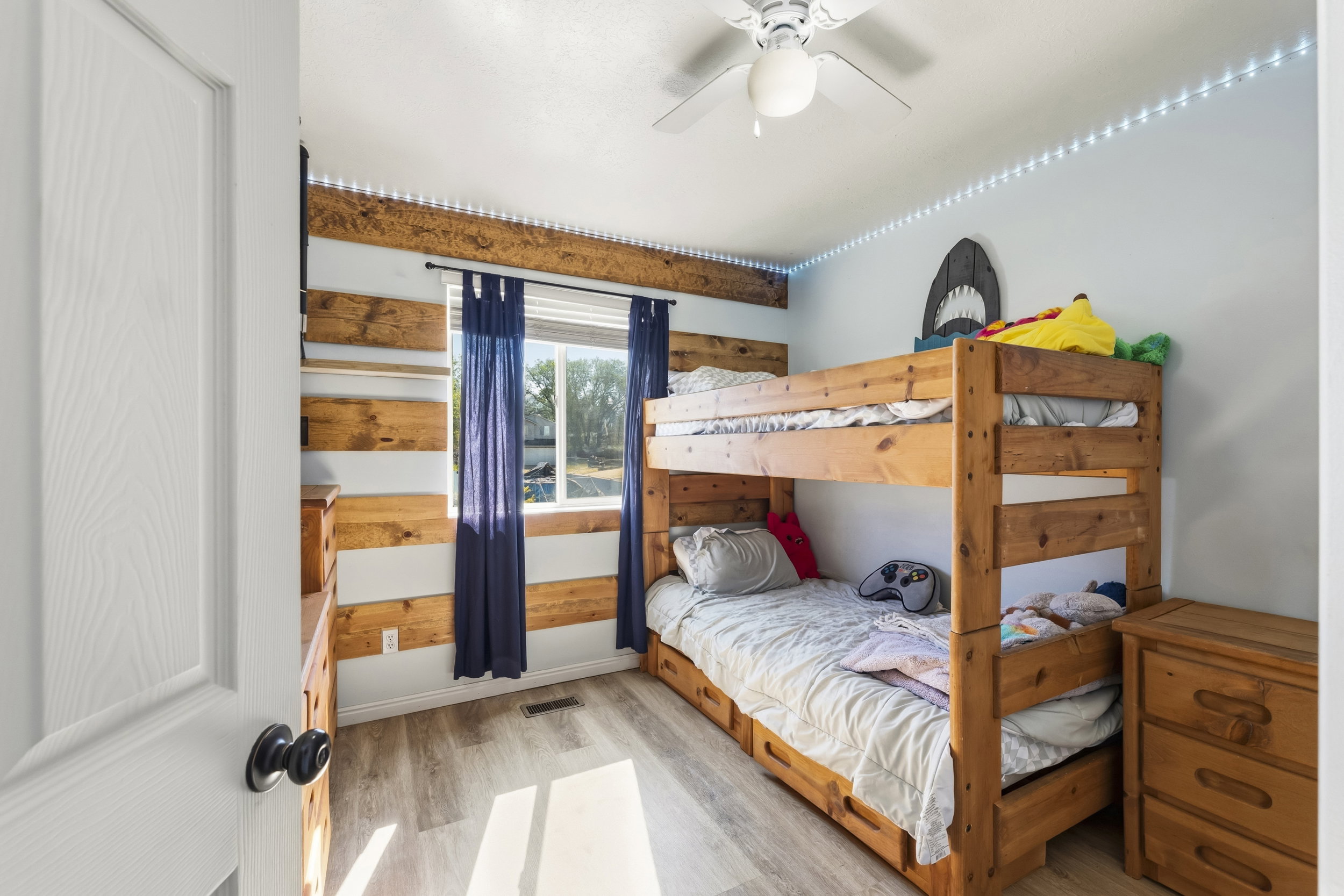 Room featuring wood-finish flooring and a ceiling fan with integrated lighting