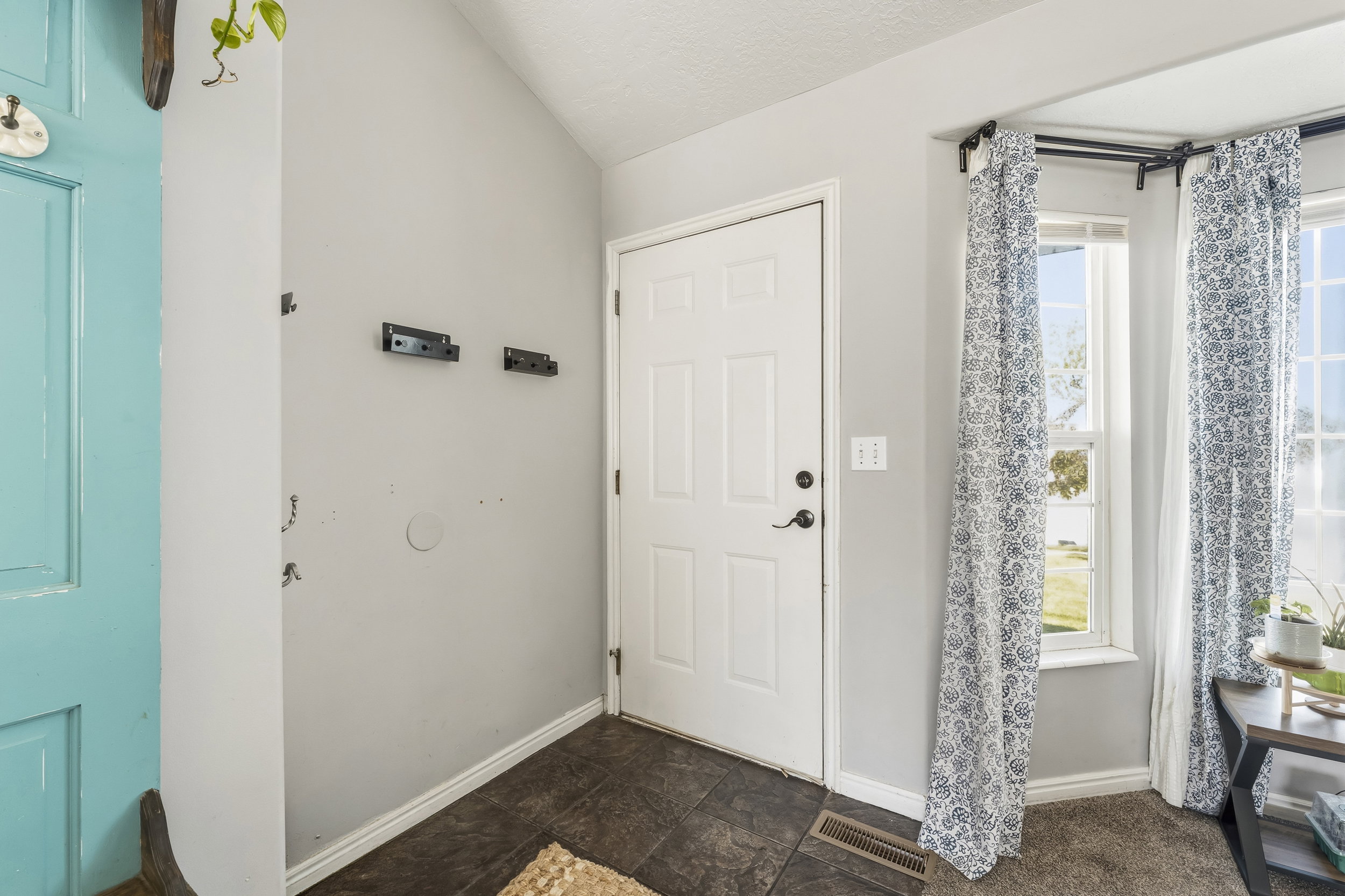 Entryway featuring a white paneled door, dark tile flooring, and a corner window arrangement