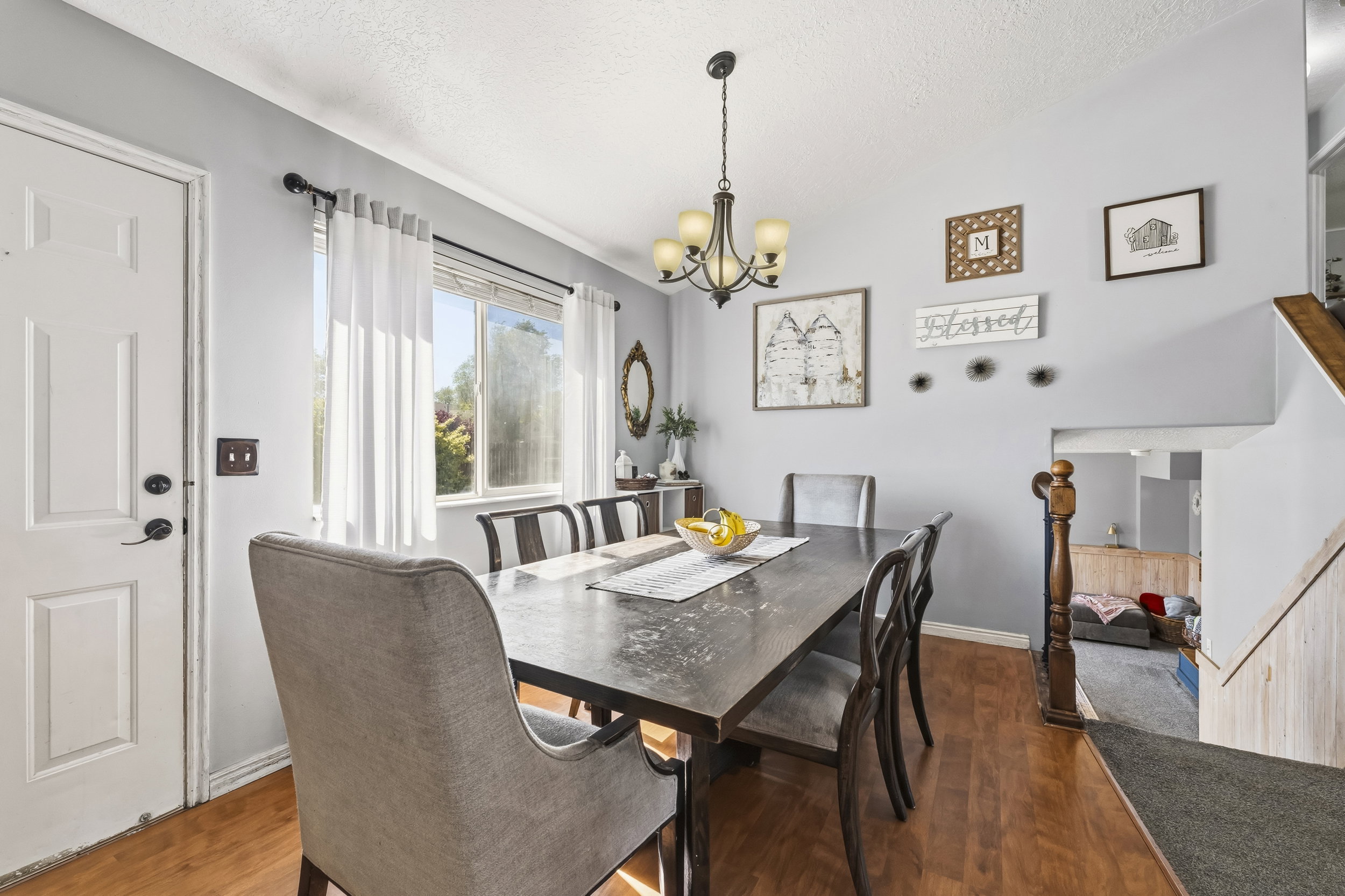 Dining area featuring wood-finish flooring, a multi-pane window, and a chandelier with glass shades