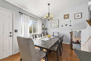 Dining area featuring wood-finish flooring, a multi-pane window, and a chandelier with glass shades