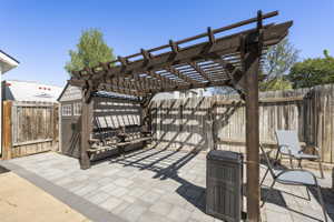 Outdoor patio featuring a dark wood pergola, a built-in bench, and a paver stone surface
