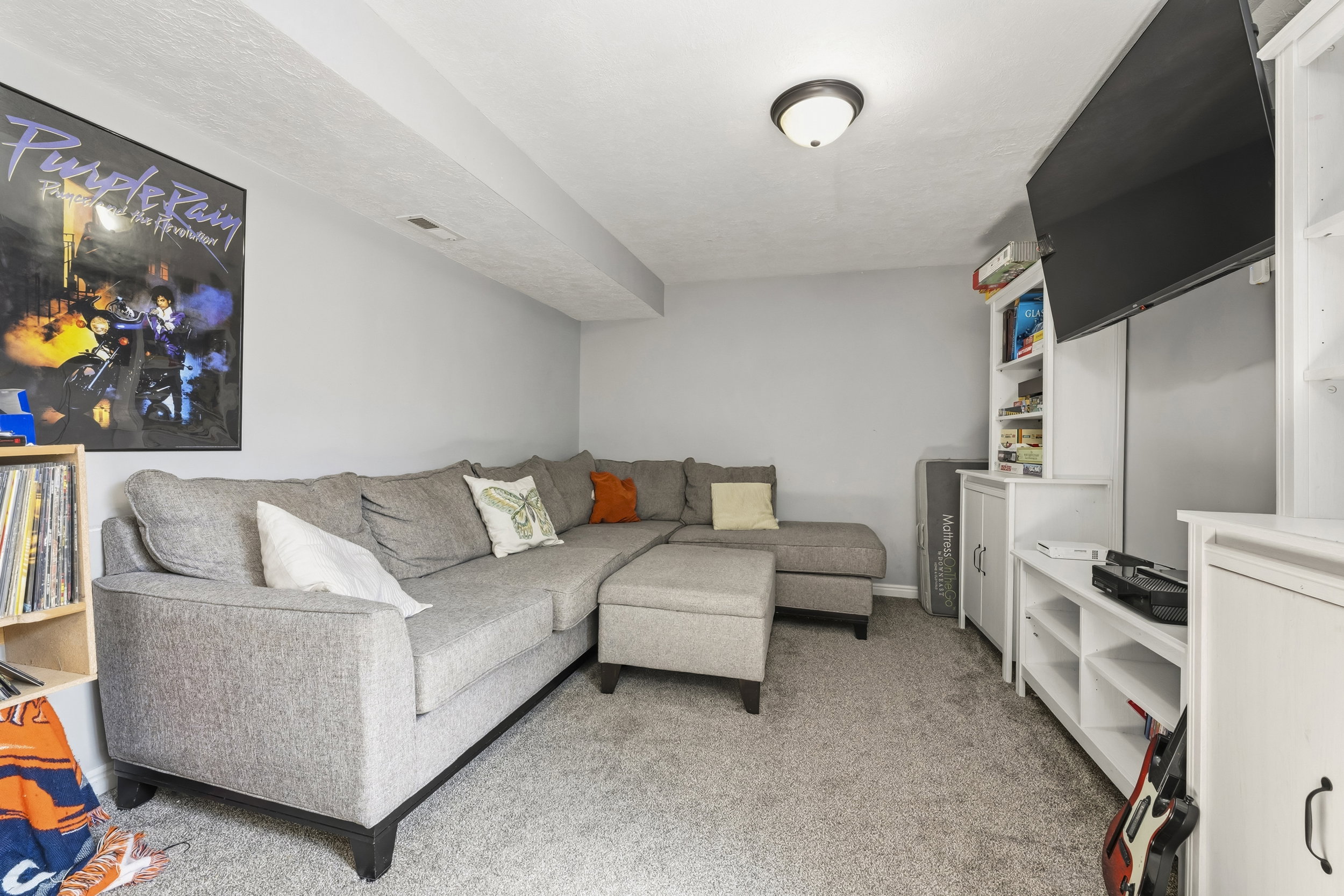 Carpeted recreation area featuring recessed lighting, light gray walls, and white built-in shelving units