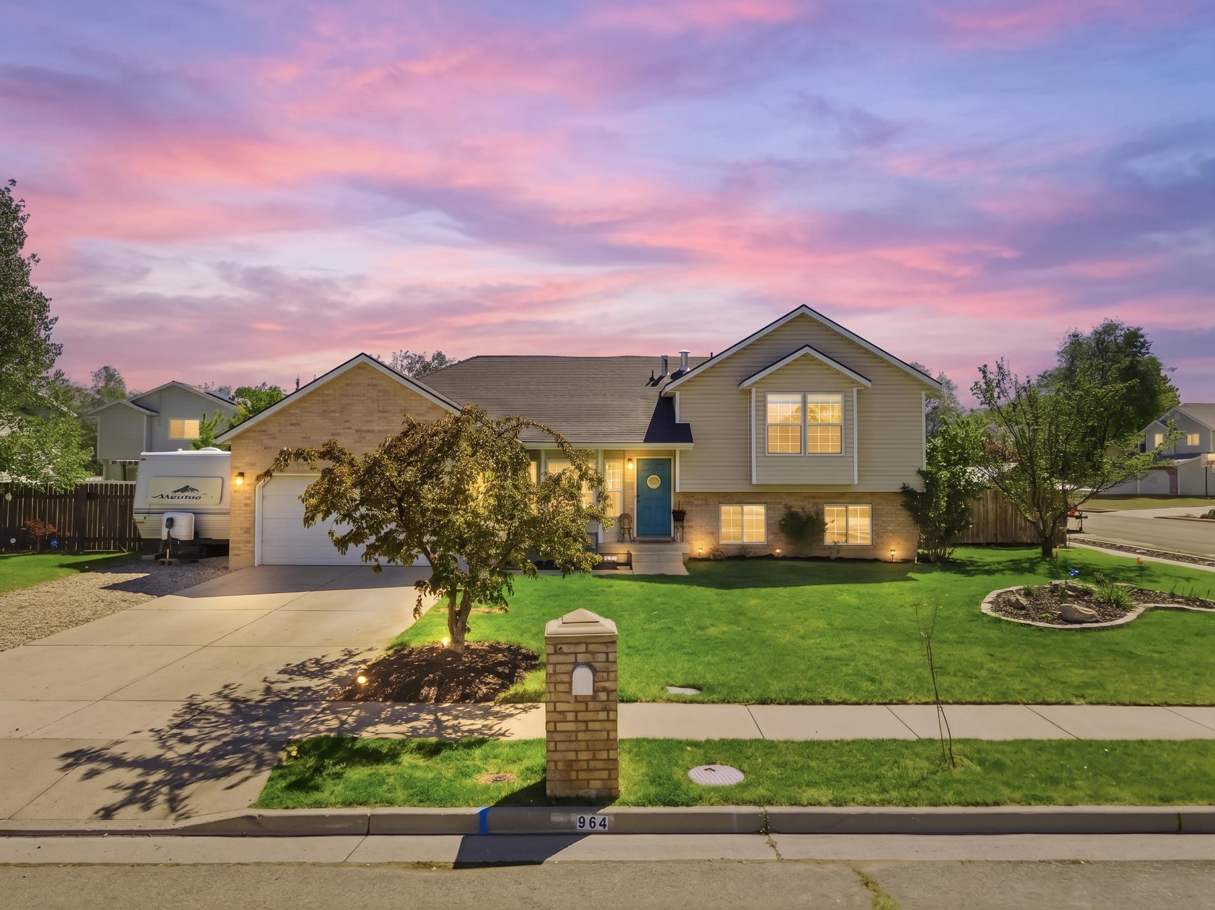 Two-story residence featuring a brick and siding exterior, an attached two-car garage, an expansive concrete driveway, a manicured front lawn, and foundational landscaping