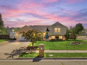 Two-story residence featuring a brick and siding exterior, an attached two-car garage, an expansive concrete driveway, a manicured front lawn, and foundational landscaping