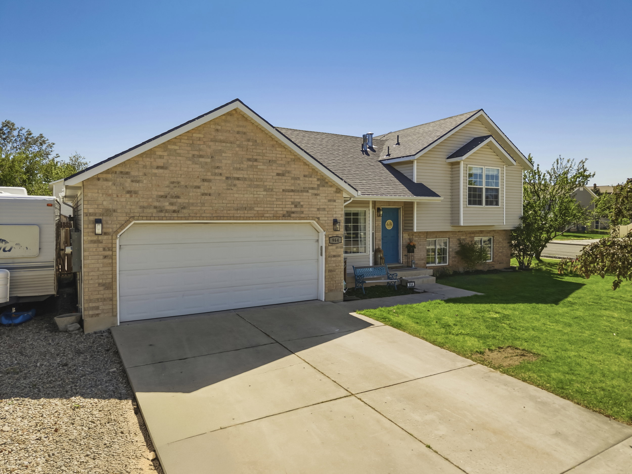 Exterior with brick and siding, featuring a two-car garage, a bright blue entry door, a bay window, and a concrete driveway