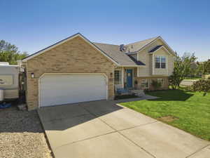 Exterior with brick and siding, featuring a two-car garage, a bright blue entry door, a bay window, and a concrete driveway