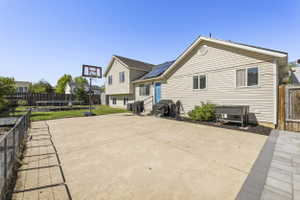 Expansive concrete patio with a paved border, leading to a manicured lawn and a fenced garden area