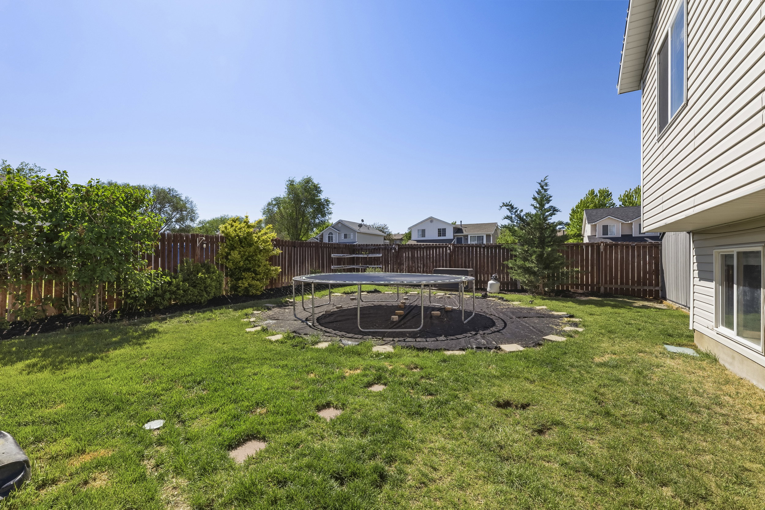Spacious backyard featuring a manicured lawn, full privacy fencing, and mature perimeter landscaping
