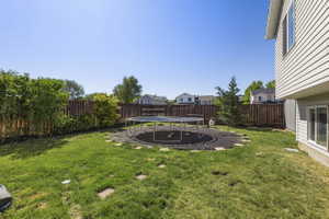 Spacious backyard featuring a manicured lawn, full privacy fencing, and mature perimeter landscaping