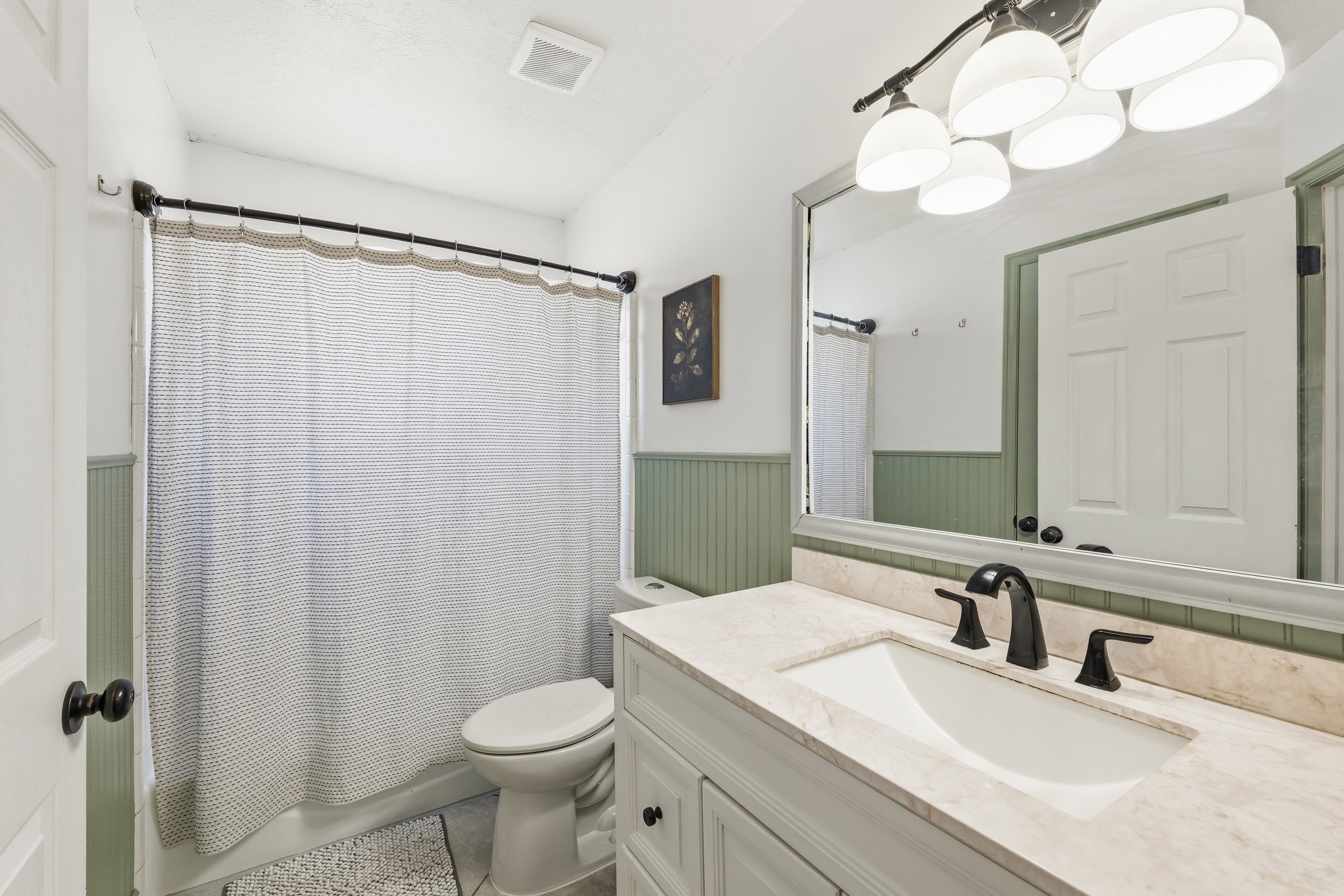 Bathroom featuring a vanity with a light-toned countertop, integrated sink, and matte black faucet