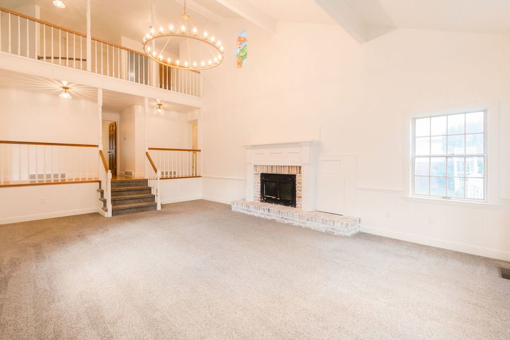 Spacious living area featuring a vaulted ceiling and an overhead chandelier