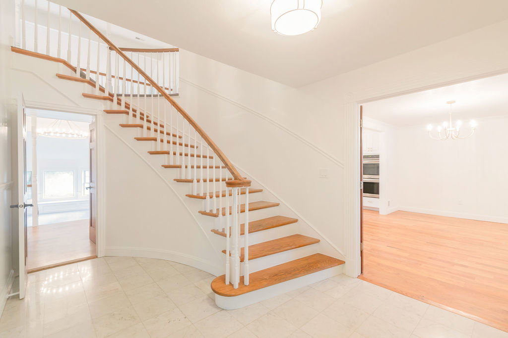 Grand staircase with light wood treads and white risers